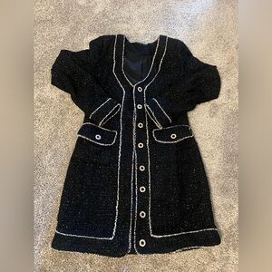This is a black tweed dress featuring white trim accents along the edges.